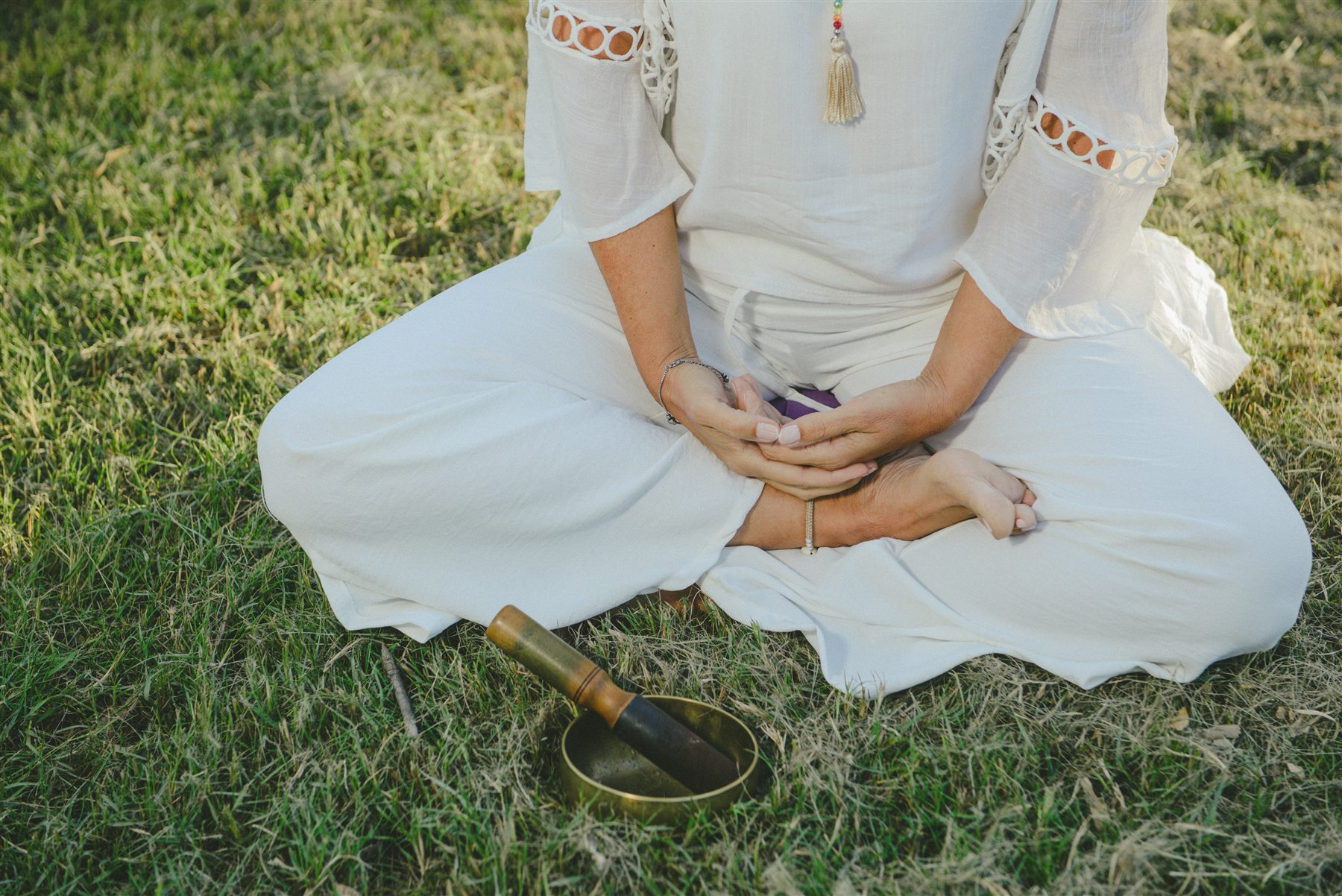 Rosana Rangone meditando sentada sobre el cesped junto a un cuenco tibetano
